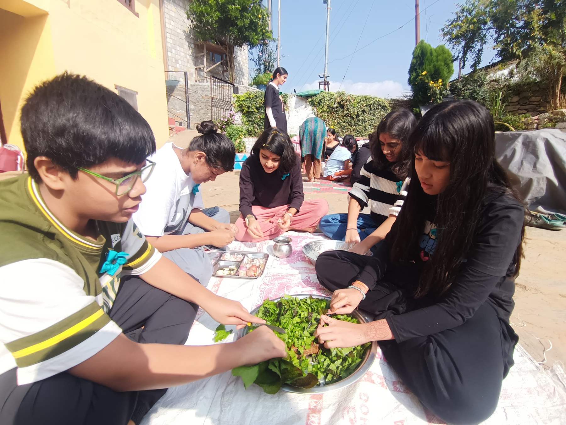 Learners washing and sorting fresh greens outdoors at Majkhali