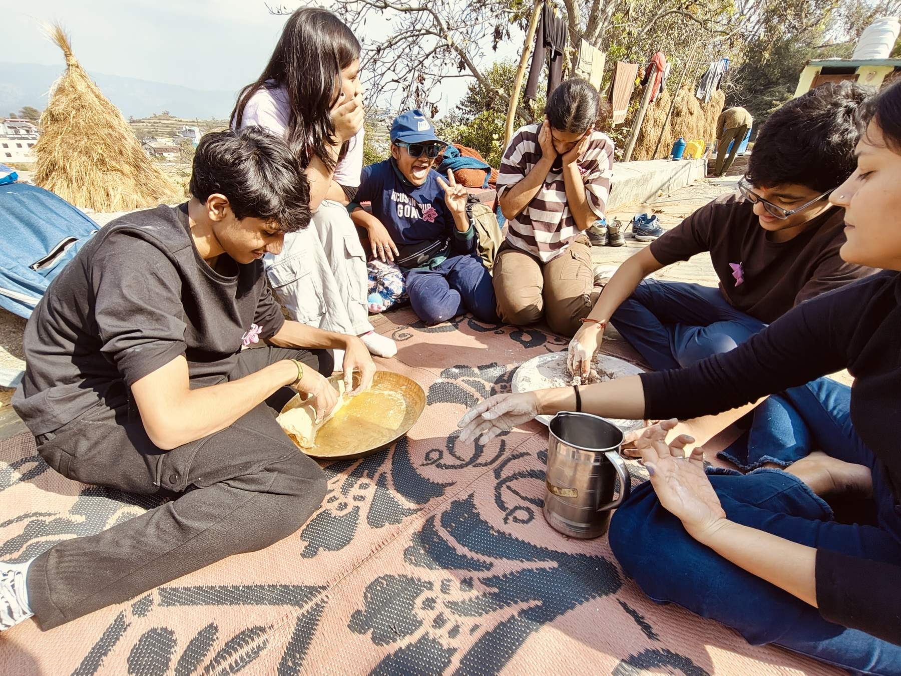 Learners grinding grain on a mat in the sun during the Majkhali rural immersion