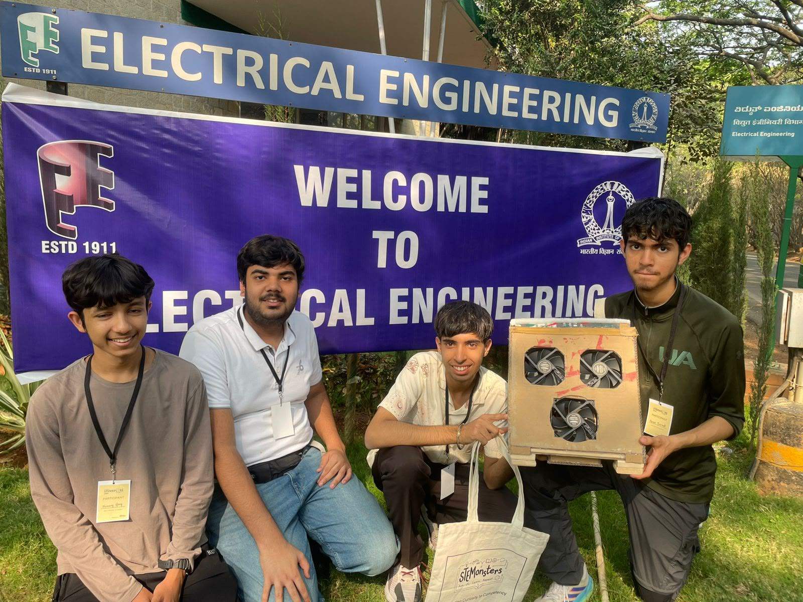 Learners holding their three-fan air purifier outside a university electrical engineering department